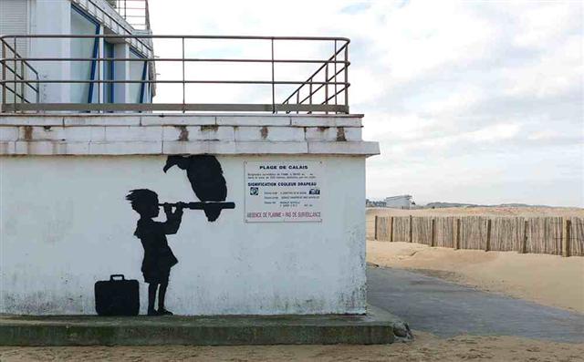カレーのビーチの近くに望遠鏡を持ったバンクシーの子供の壁画は、英国を指しています